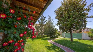 Un jardin avec un mur en briques, une pergola en bois et un sentier.