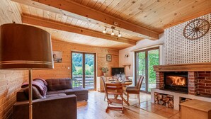 Un intérieur de chalet chaleureux avec un plafond en bois, une cheminée, un coin repas et un canapé.