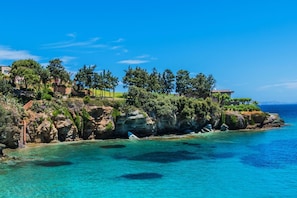 A coastal property with a rocky cliff, clear blue sea, and a row of houses with a garden. - Villa Eolos Crete in Heraklion (Malevizi)