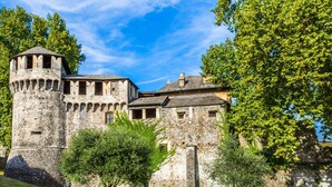 A historic stone castle with a prominent tower, surrounded by well-maintained grass and trees. - Rebecca Garden in Lugano (Lugano)