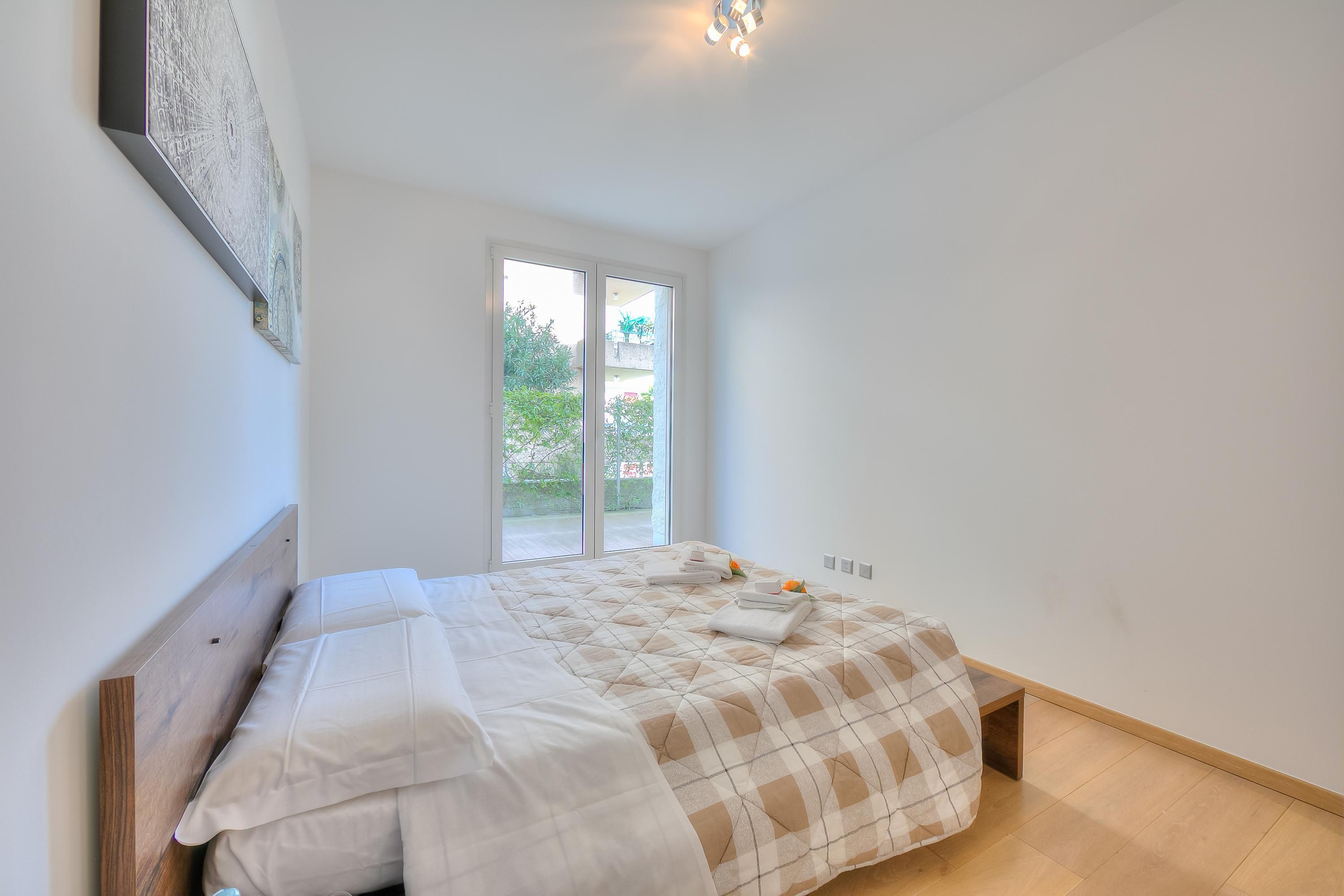 A bedroom with a bed, a window, and a door.