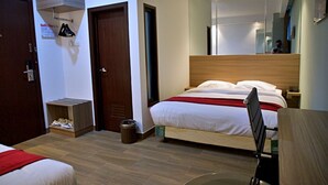 A hotel room with a bed, a wooden headboard, a nightstand, a mirror, and a small trash bin. - THE SATO HOTEL (Kudus)