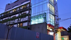 A modern hotel with a glass facade and a colorful rooftop. - THE SATO HOTEL (Kudus)