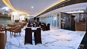 A modern restaurant with marble flooring, leather seating, and a long counter. - THE SATO HOTEL (Kudus)