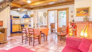 A spacious living area with a high ceiling, wooden beams, and a dining area with a table set for four. - Hawthorn apt With Shared Pool Family fun (Castiglione del Lago)