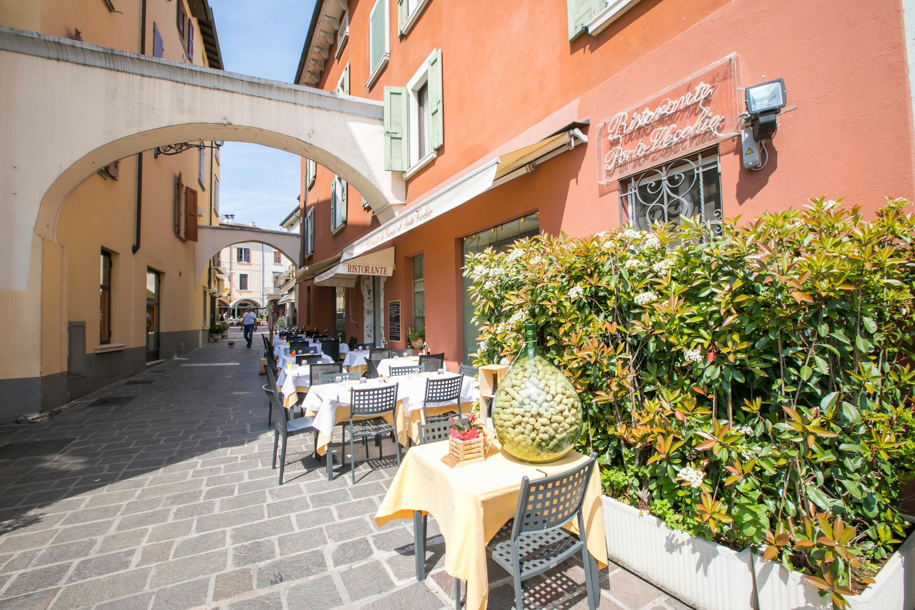 An outdoor café with tables and chairs, a large pineapple centerpiece, and a building with a sign reading "Ristorante".