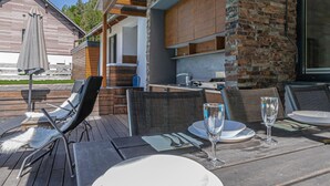 An outdoor dining area with wooden tables and chairs, a brick wall, and a large window. - Pool Villa Katja Kranjska Gora (Kranjska Gora)
