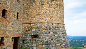 Une tour en pierre à base circulaire et au sommet plat, dotée de nombreuses fenêtres et d’une petite porte.