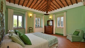 Une chambre à coucher comprenant un lit, une commode, une chaise et deux fenêtres.