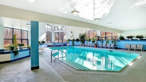 Una piscina interior con agua cristalina, rodeada de sillones de descanso y plantas en macetas.