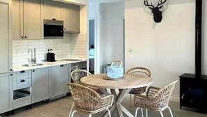 Une cuisine moderne avec des meubles blancs, un four à micro-ondes et un coin repas comprenant des chaises en osier et une table ronde.