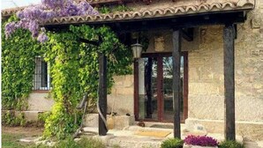 Un bâtiment en pierre avec un toit en tuiles, une porte en bois et un porche abrité.