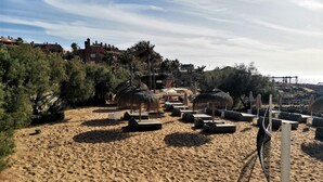 Une plage avec des transats, des parasols et un filet de volley-ball.