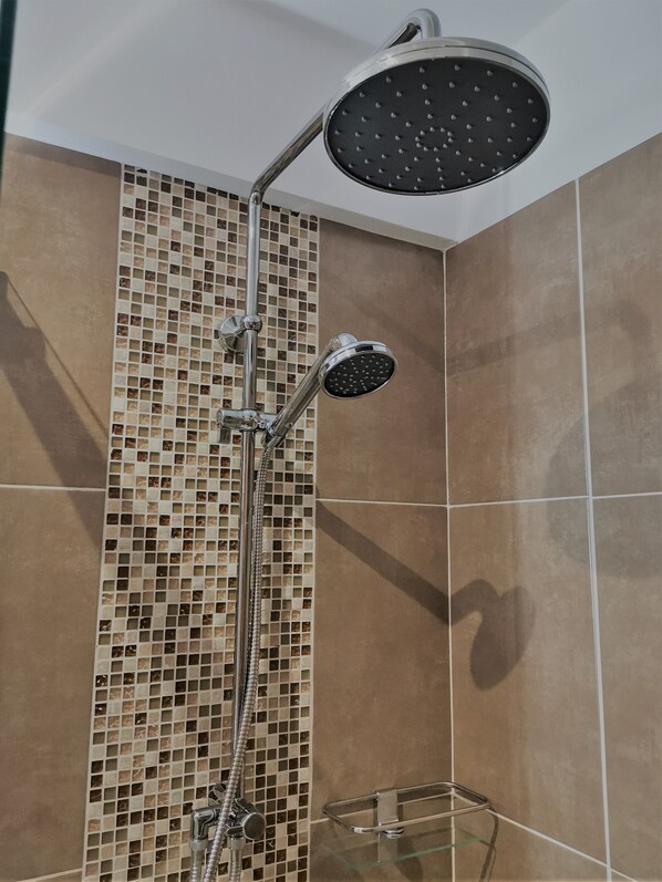 Ducha con cabezal de ducha tipo lluvia y cabezal de ducha manual, plato de ducha de vidrio y pared con diseño de mosaico.