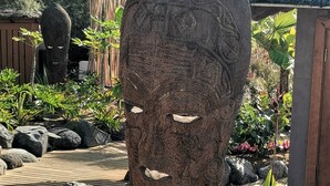 Une sculpture en pierre représentant un visage sculpté, située dans un jardin.