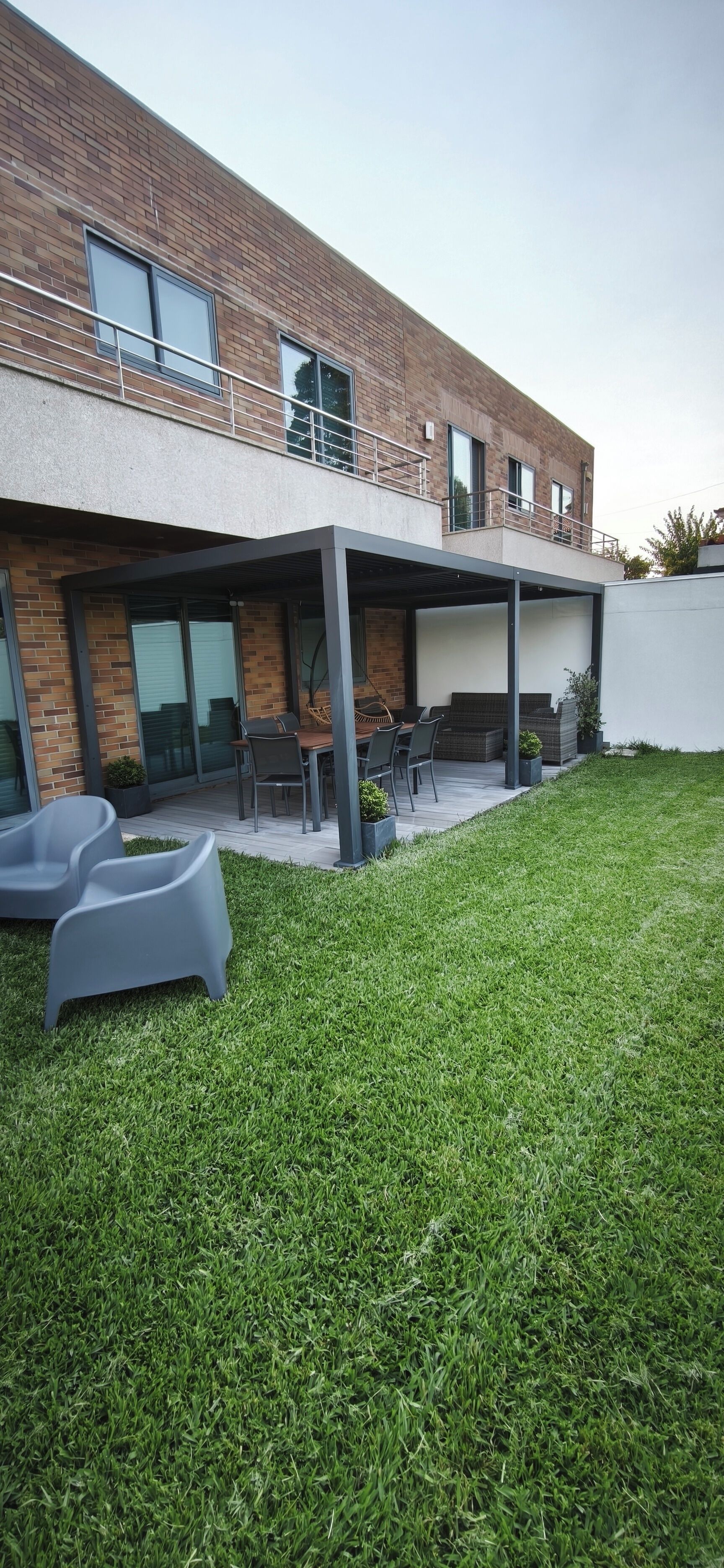 A modern building with a covered patio area, outdoor seating, and a well-maintained lawn.