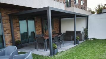 A modern building with a covered patio area, outdoor seating, and a well-maintained lawn.