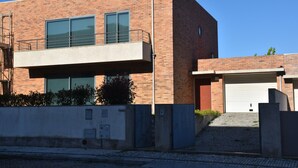 Un bâtiment moderne à deux étages, doté d’un toit plat, d’un balcon à l’étage supérieur et d’une porte de garage sur le côté droit.