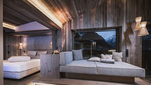 Une chambre moderne avec un grand lit, un canapé-lit et une grande fenêtre donnant sur les montagnes.