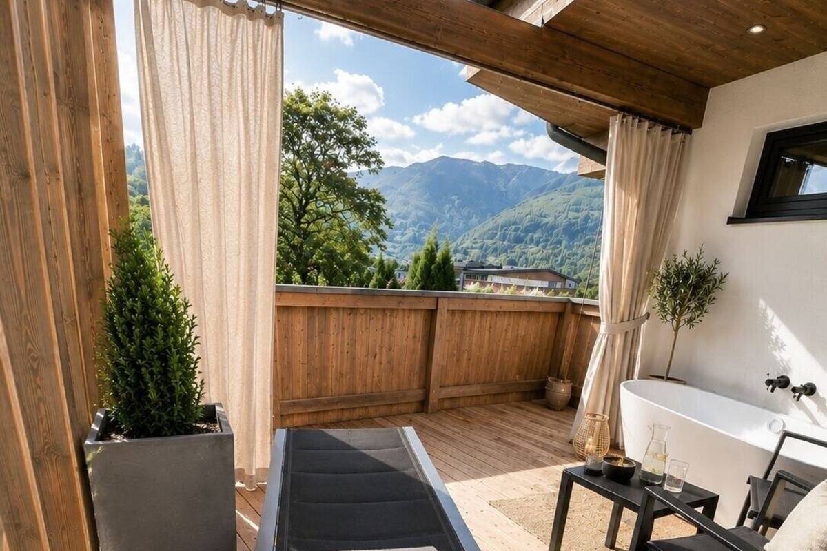 Eine Holzterrasse mit einer Couch, einem kleinen Tisch, einem Sessel und einer Badewanne.