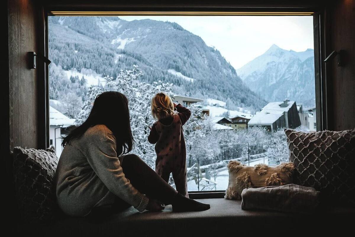 Ein Zimmer mit einem großen Fenster mit Blick auf eine verschneite Berglandschaft.