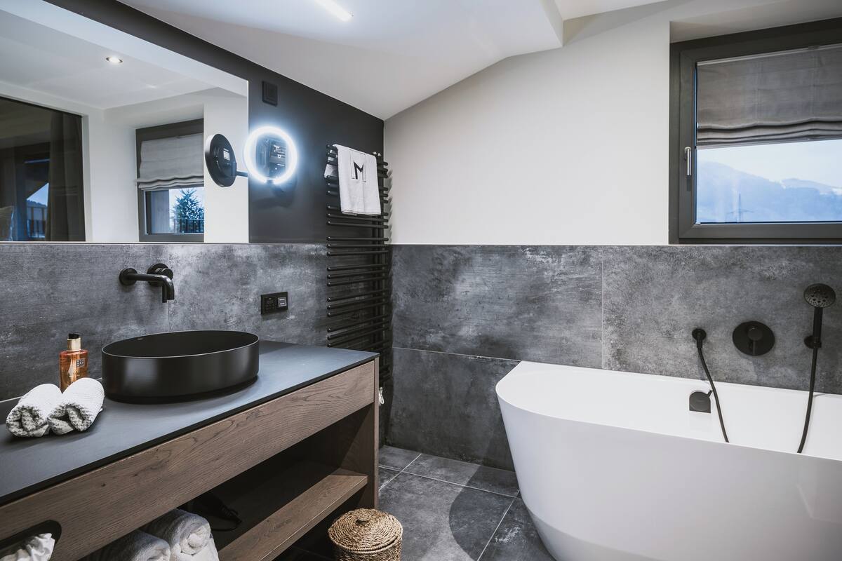 Ein modernes Badezimmer mit einer freistehenden Badewanne, einem runden Waschbecken und einem großen Spiegel.