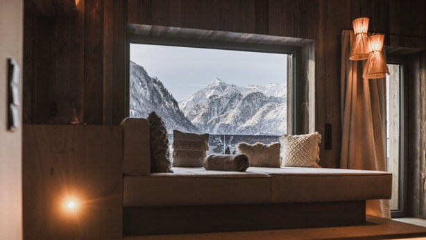 Un coin salon confortable avec vue sur les montagnes enneigées, grâce à une grande fenêtre.