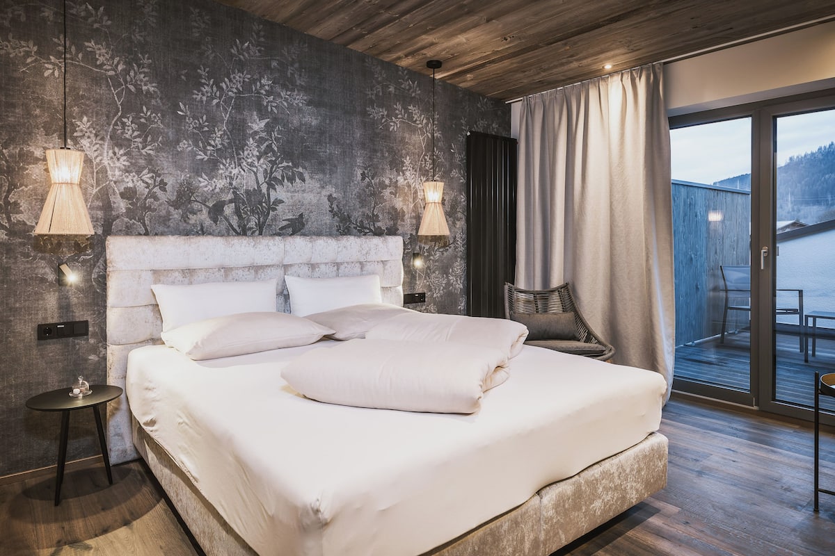 Ein modernes Schlafzimmer mit einem großen Bett, einem Holzkopfende, einem Nachttisch und Blick auf einen Balkon.