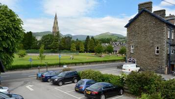 A parking lot with several cars, a stone building, and a church in the background.