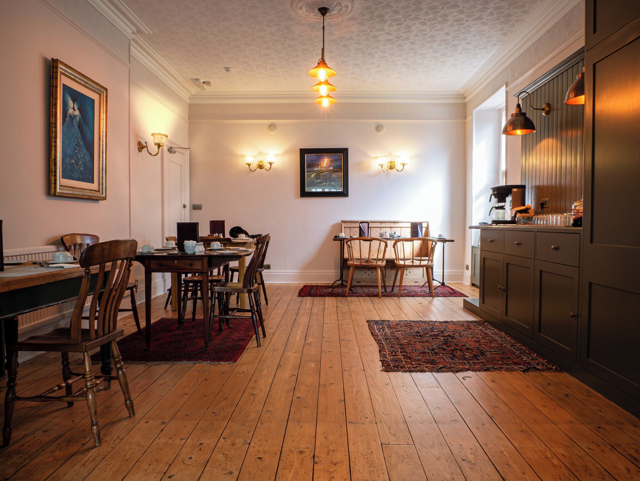A dining area with wooden flooring, a table set with chairs, and a chandelier.