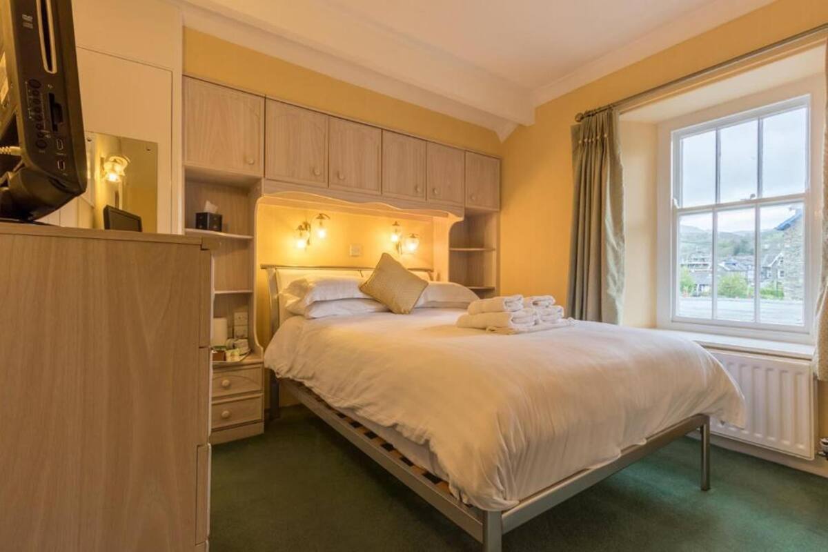 A hotel room with a single bed, bedside tables, a wardrobe, and a window with a view.