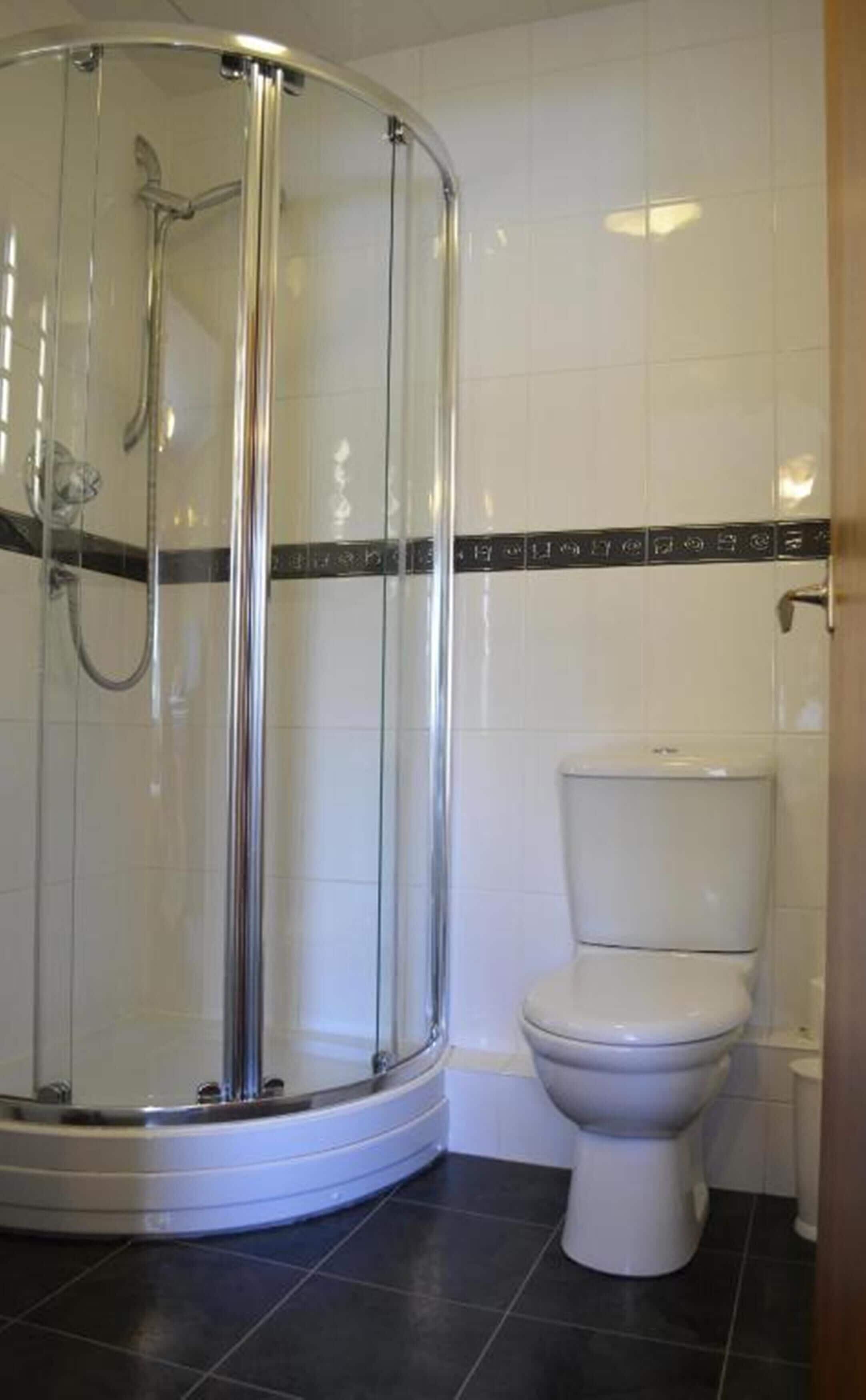 Une salle de bain avec une douche à parois de verre, des toilettes et des murs carrelés.