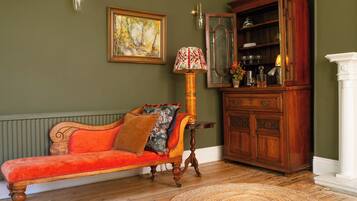 A room with a red sofa, a wooden cabinet, a lamp, and a painting on the wall.