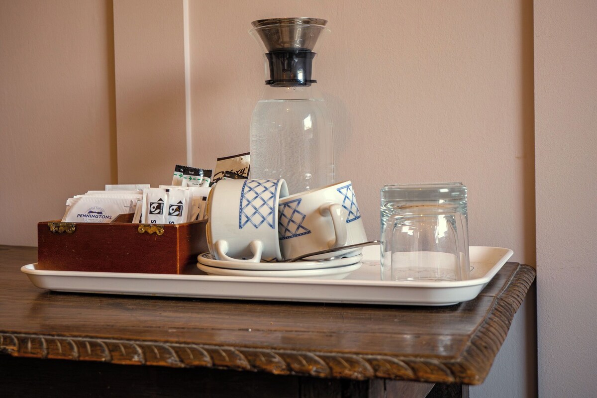 Un plateau contenant une cafetière, un bocal en verre, une tasse et une boîte de sachets de thé.