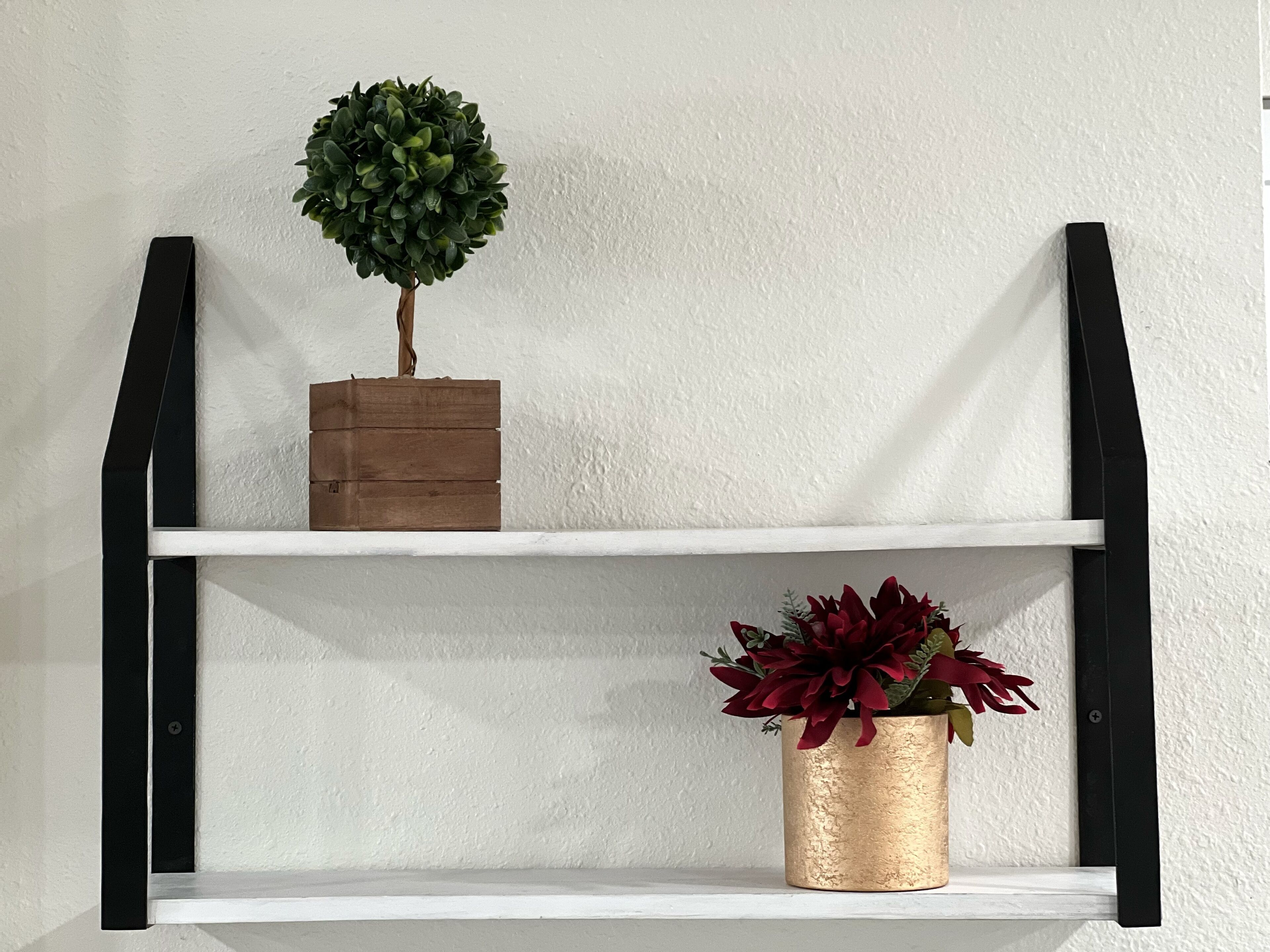 Een plankje met een klein potplantje en een decoratieve doos.