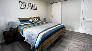 A bedroom with a bed, nightstands, a dresser, a sliding door, and three framed artworks on the wall.