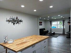 A modern living room with a wooden dining table, grey sofa, and a black couch.