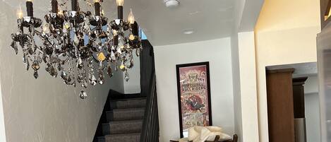 A staircase with a dark carpet and black balusters, leading to a landing with a framed poster and a small table.