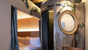 Un baño rústico con lavamanos de madera, un espejo y una cama con cortina.