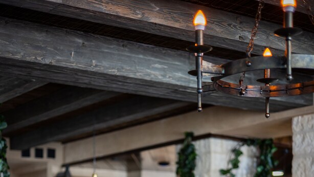 Interior de restaurante con mesas de madera, sillas de metal y lámparas colgantes.