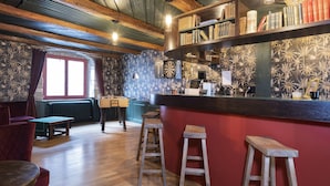 Un rincón acogedor con barra, muebles de madera, un dardo y una estantería llena de libros.