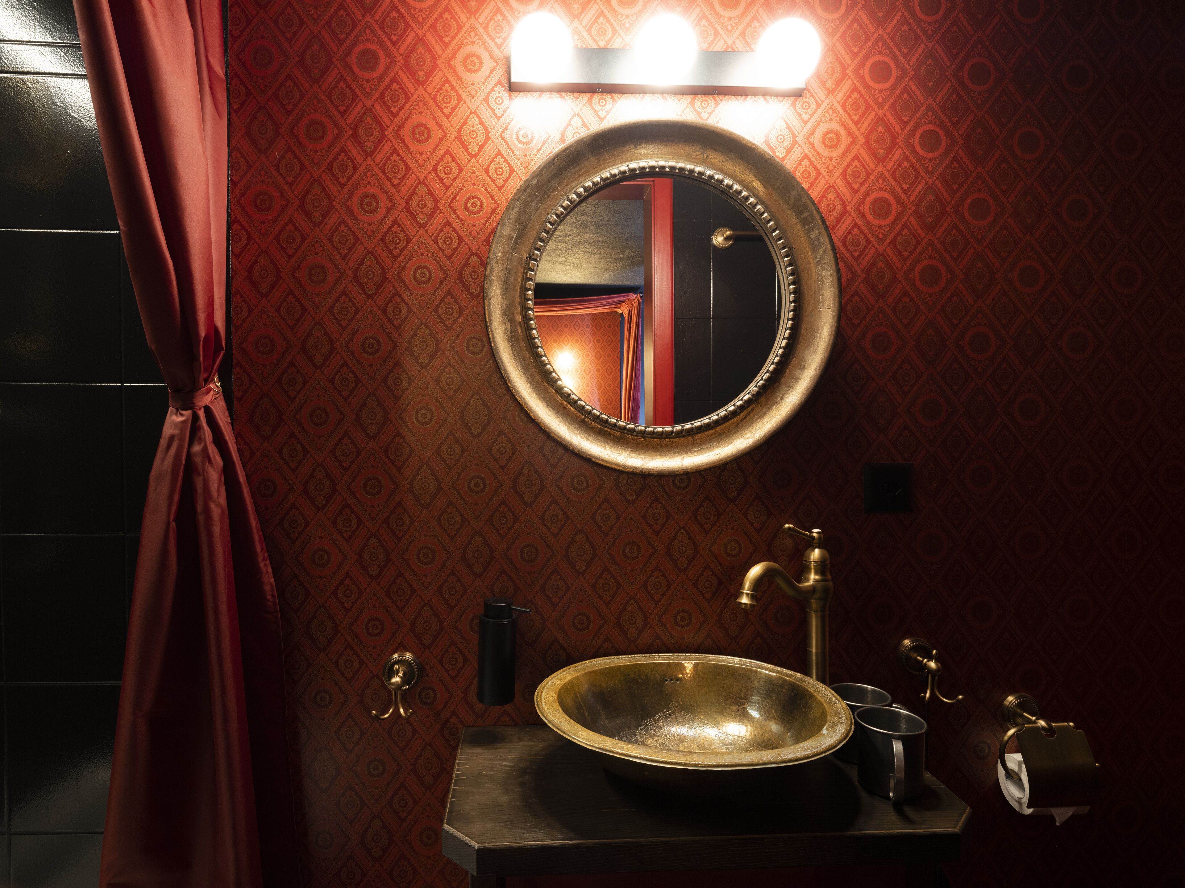 Un baño con un espejo redondo, un lavabo y un perchero para toallas.