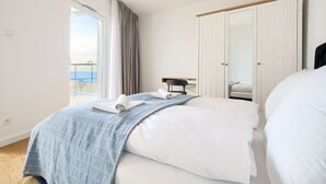 A bedroom with a large bed, a desk, and a wardrobe. - Apartamenty Sun&Snow Przy Plaży (Mielno)