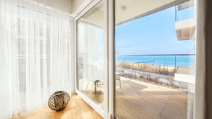 A room with a large sliding glass door leading to a balcony with a view of the sea. - Apartamenty Sun&Snow Przy Plaży (Mielno)