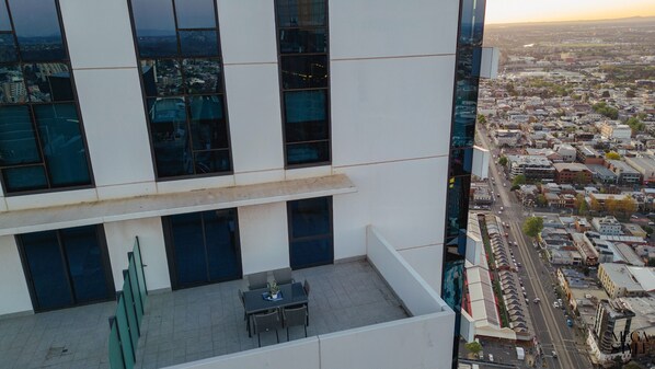 Un edificio moderno con ventanas amplias y un área de terraza en la azotea.