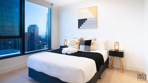 Une chambre moderne avec un grand lit, une vue sur la ville et un décor minimaliste.