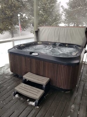 A hot tub on a wooden deck with a view of trees and a flag. - Lake House In Cascade w/ Hot Tub (Cascade)
