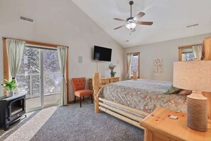 A bedroom with a bed, a television, a ceiling fan, a fireplace, and a view through the window. - Lake House In Cascade w/ Hot Tub (Cascade)
