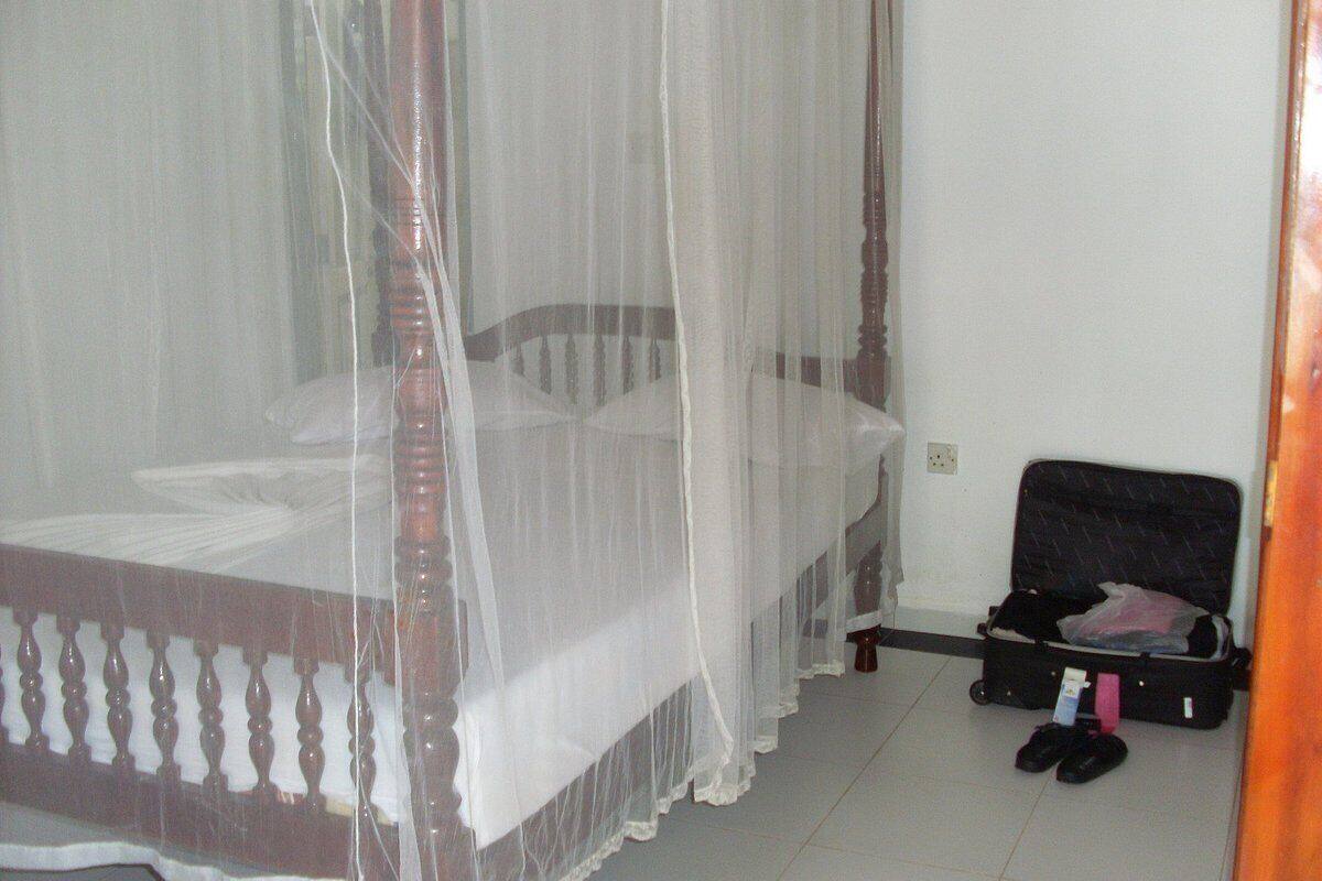 A room with a four-poster bed, a suitcase, and a pair of shoes on the floor.