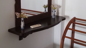 A wooden chair and a small table with a vase and remote control.